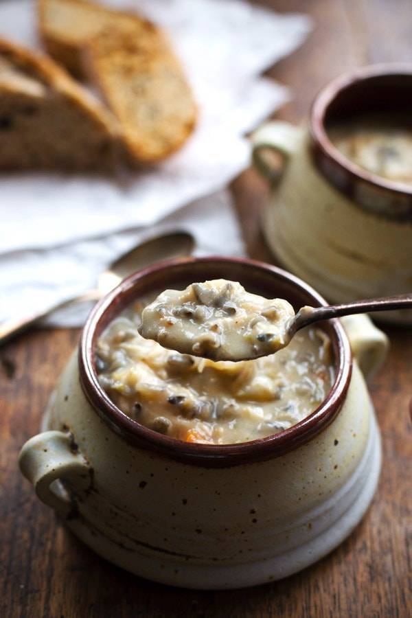 Spoon scooping up chicken wild rice soup from a bowl. 