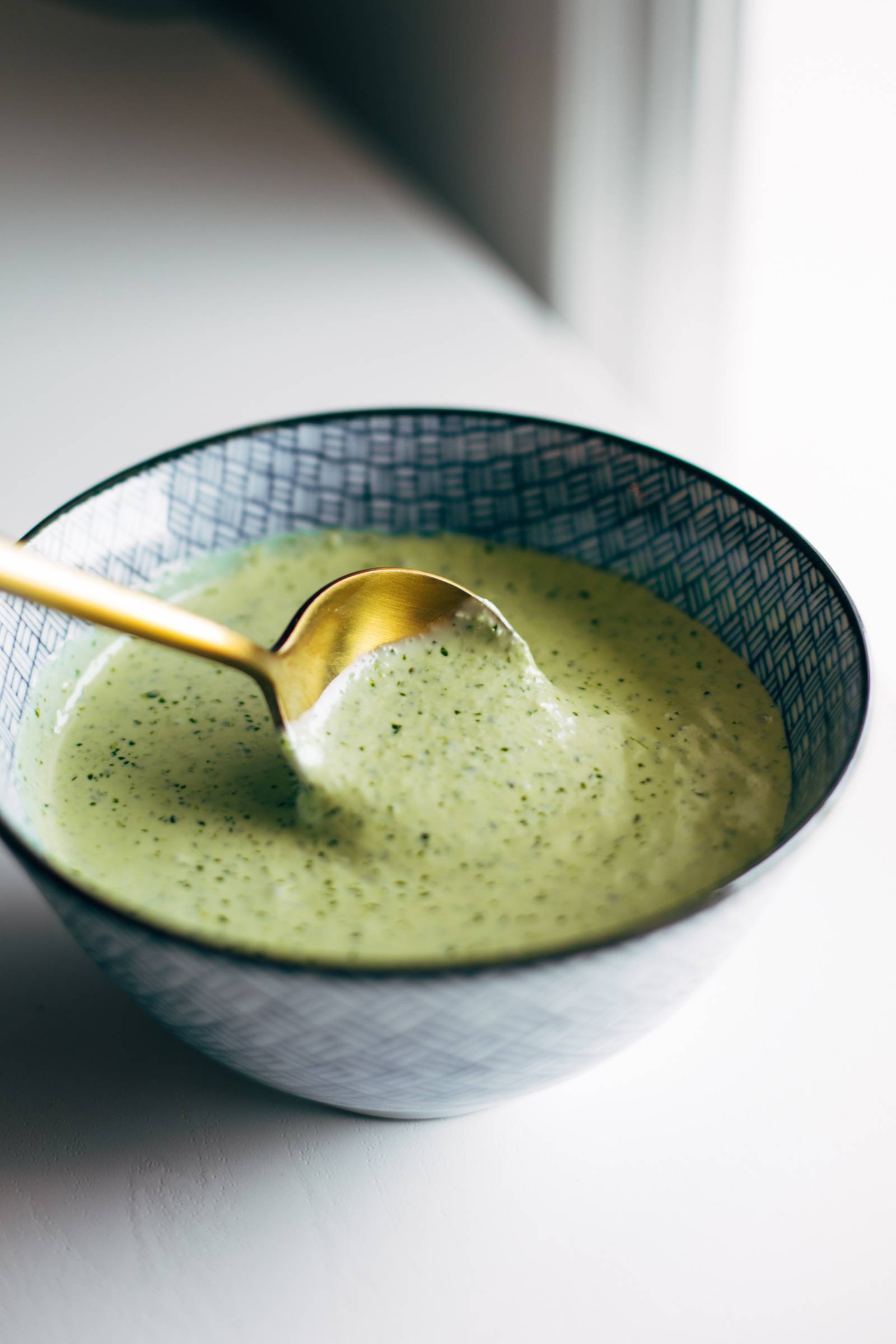 Gold spoon dips into bowl of aji verde