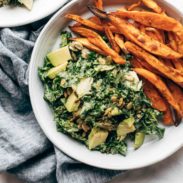 Avocado Kale Caesar Salad on a plate with sweet potato fries.