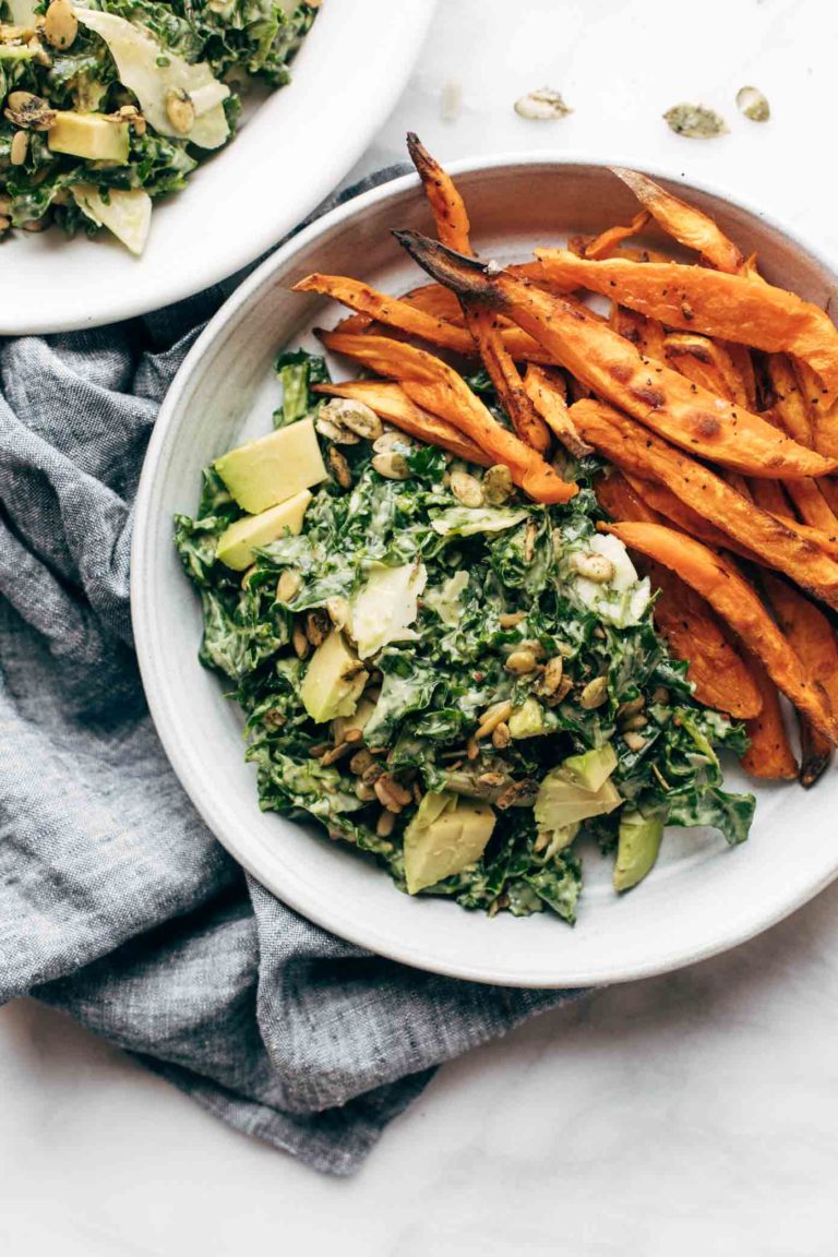 Avocado Kale Caesar Salad on a plate with sweet potato fries.