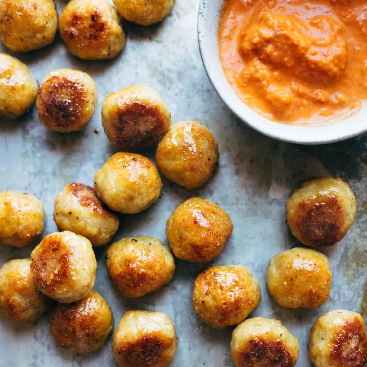 Baked Chicken Meatballs on a sheet pan with sauce.