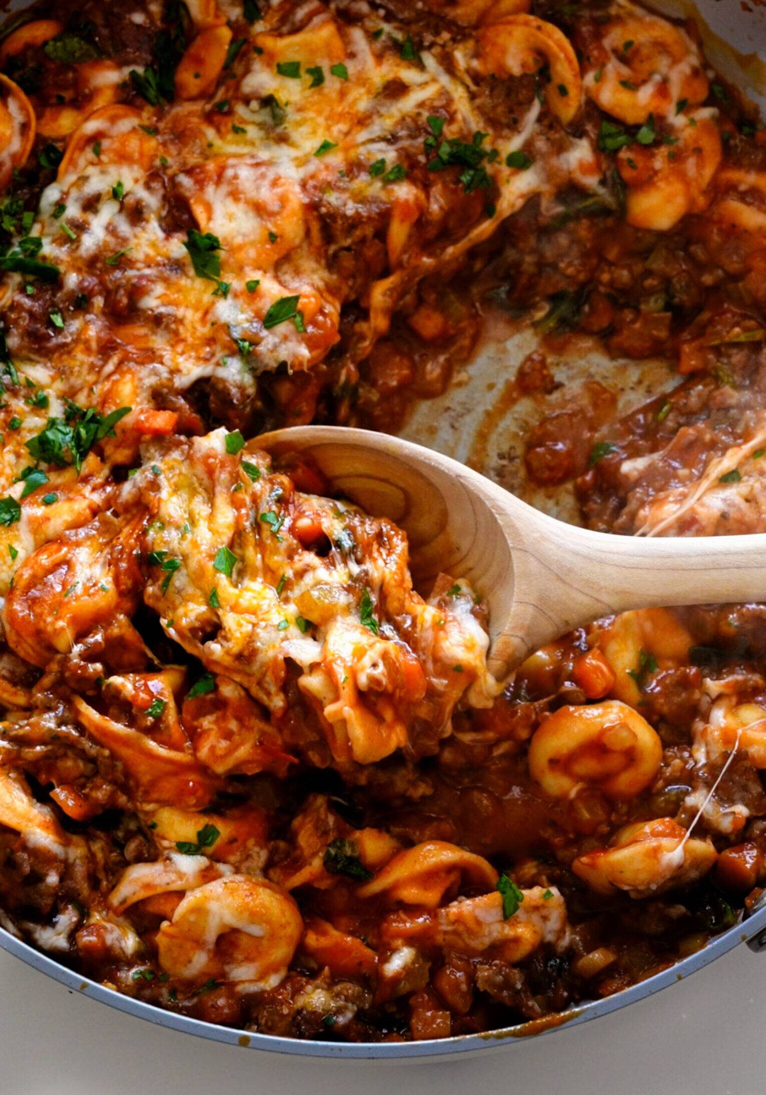 Baked Tortellini with Sausage being scooped out of the pan with melty cheese!