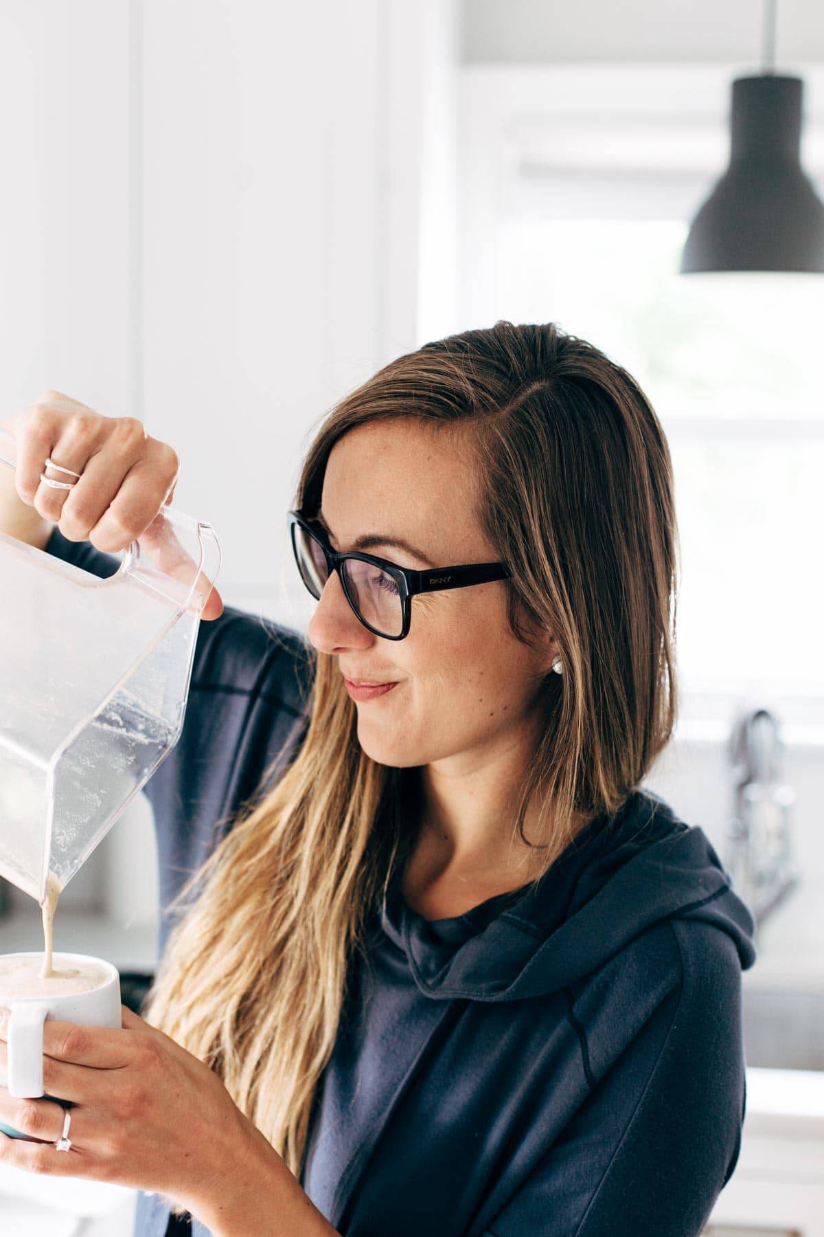 Woman pouring Cashew Coffee into a mug from a blender.