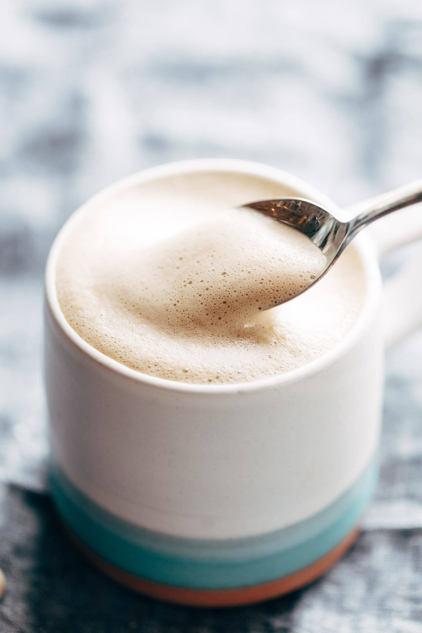 Cashew Coffee in a mug with foam on a spoon.