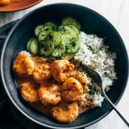 A bowl of shrimp and greens with some rice.