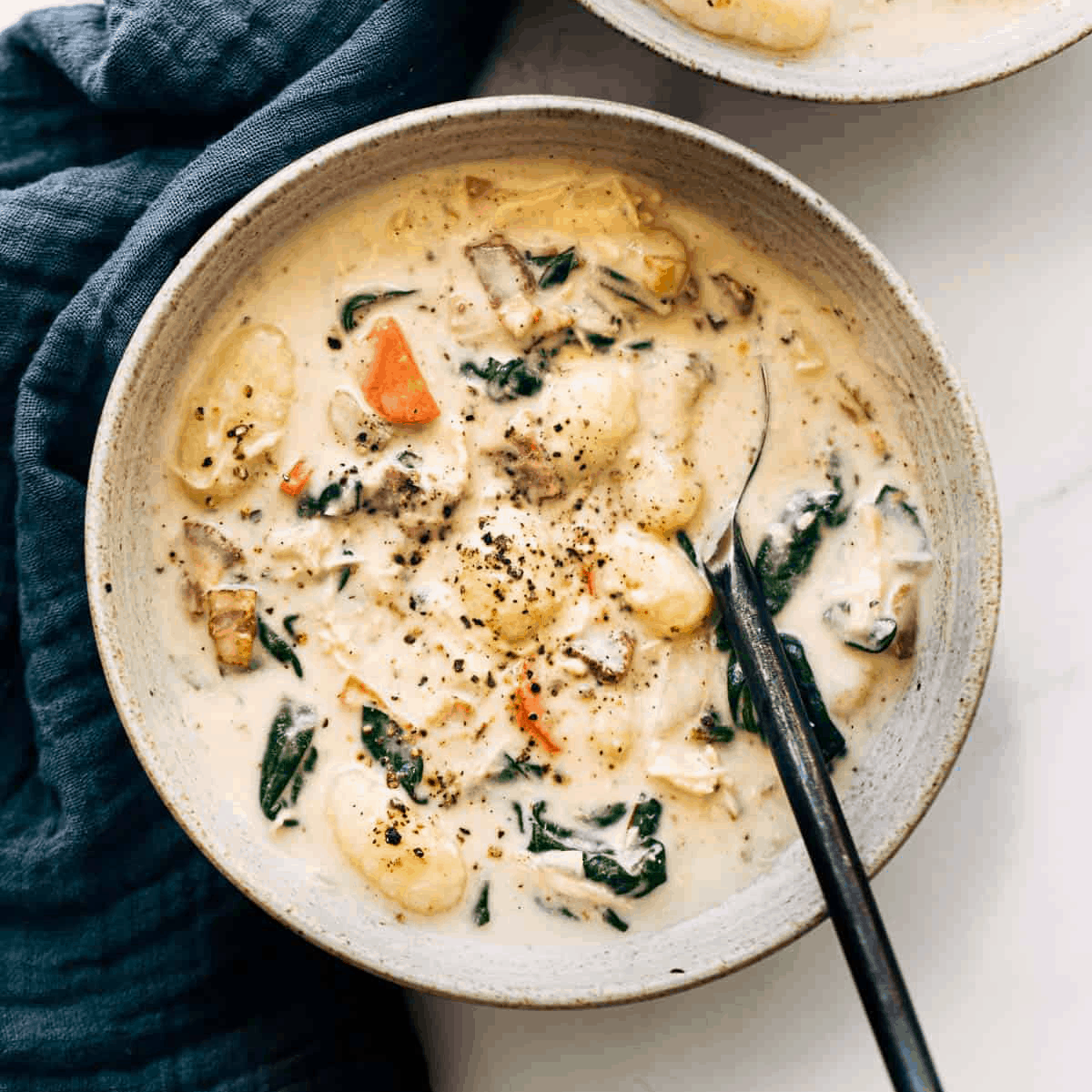 Creamy gnocchi soup in a bowl with a spoon.