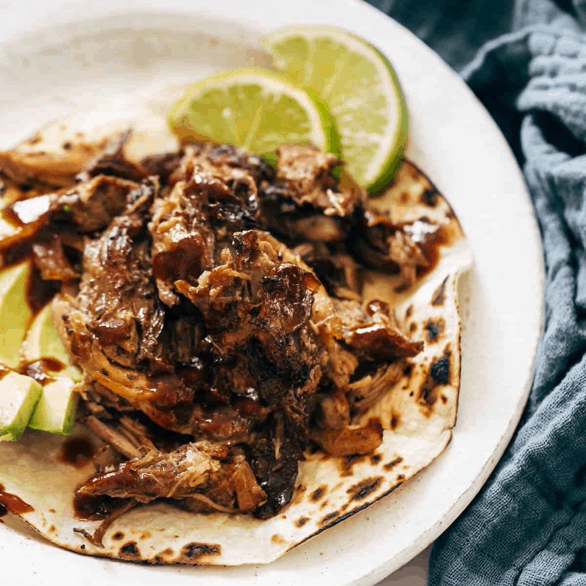 Crockpot carnitas on a plate with lime.