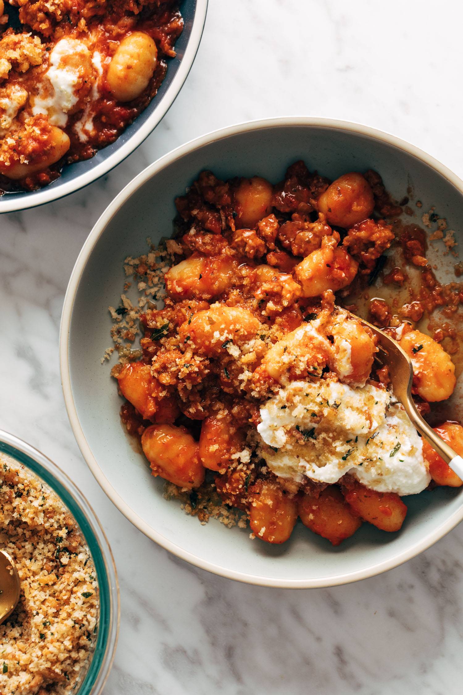 Gnocchi with red and sauce and ricotta in bowl with a fork.