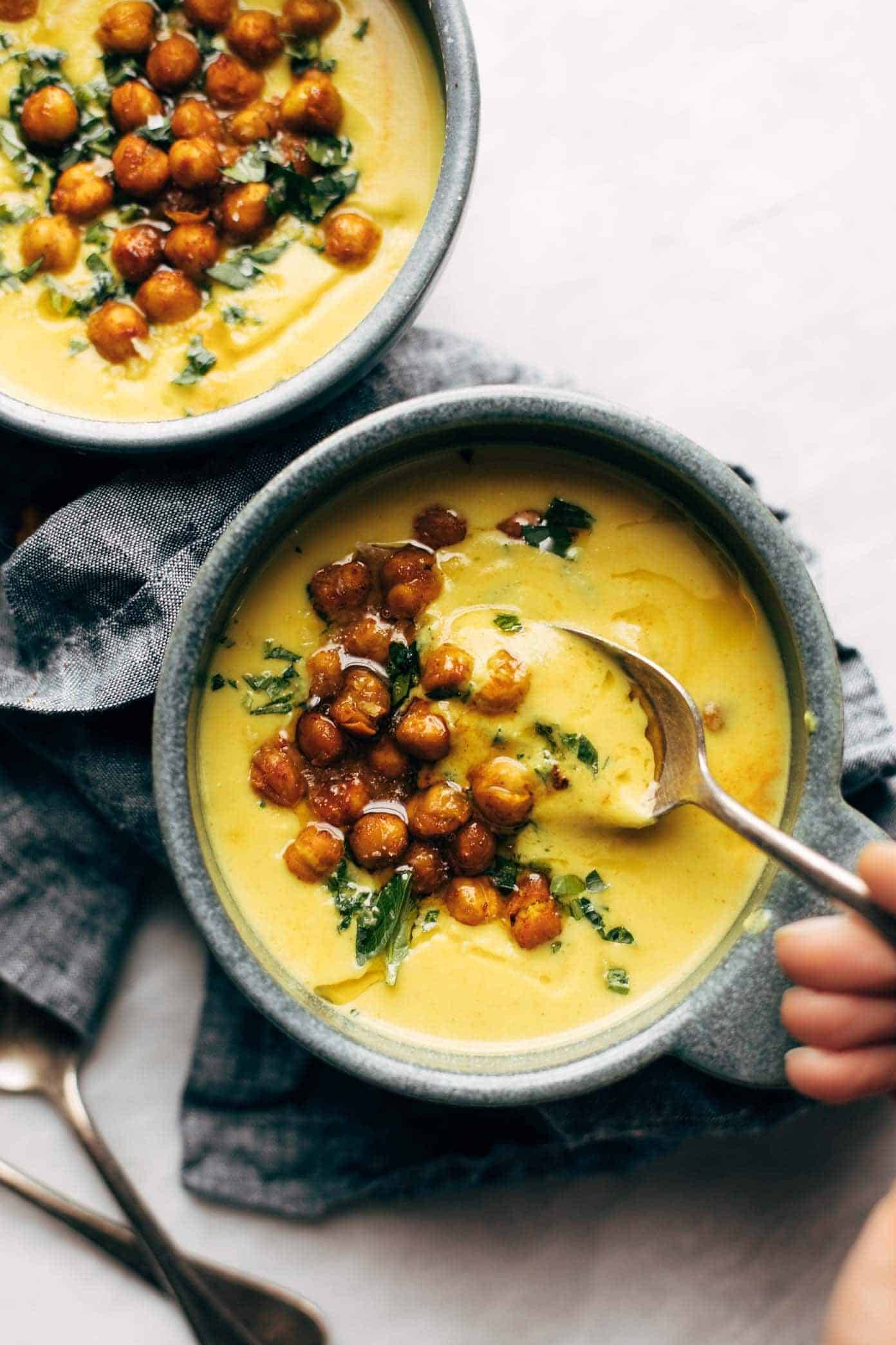 Two Bowls of Golden Soup with a spoon.