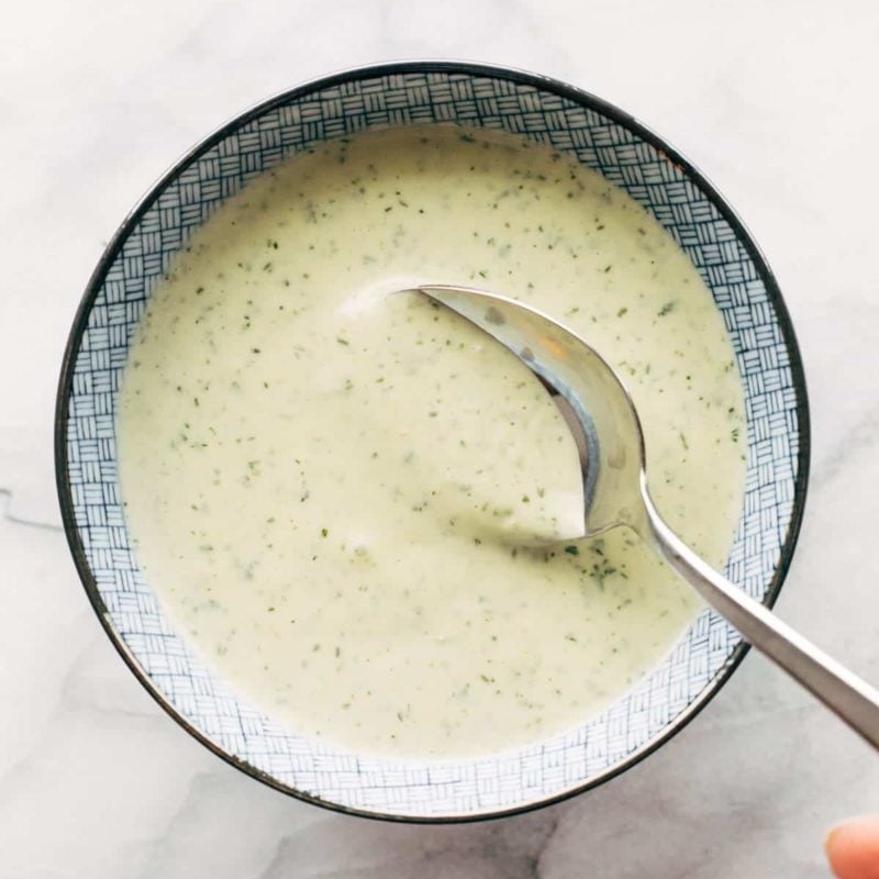 A spoon stirring a jalapeno ranch in a bowl.