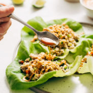 Chicken lettuce cups on plate with hand and fork going in for a bite.