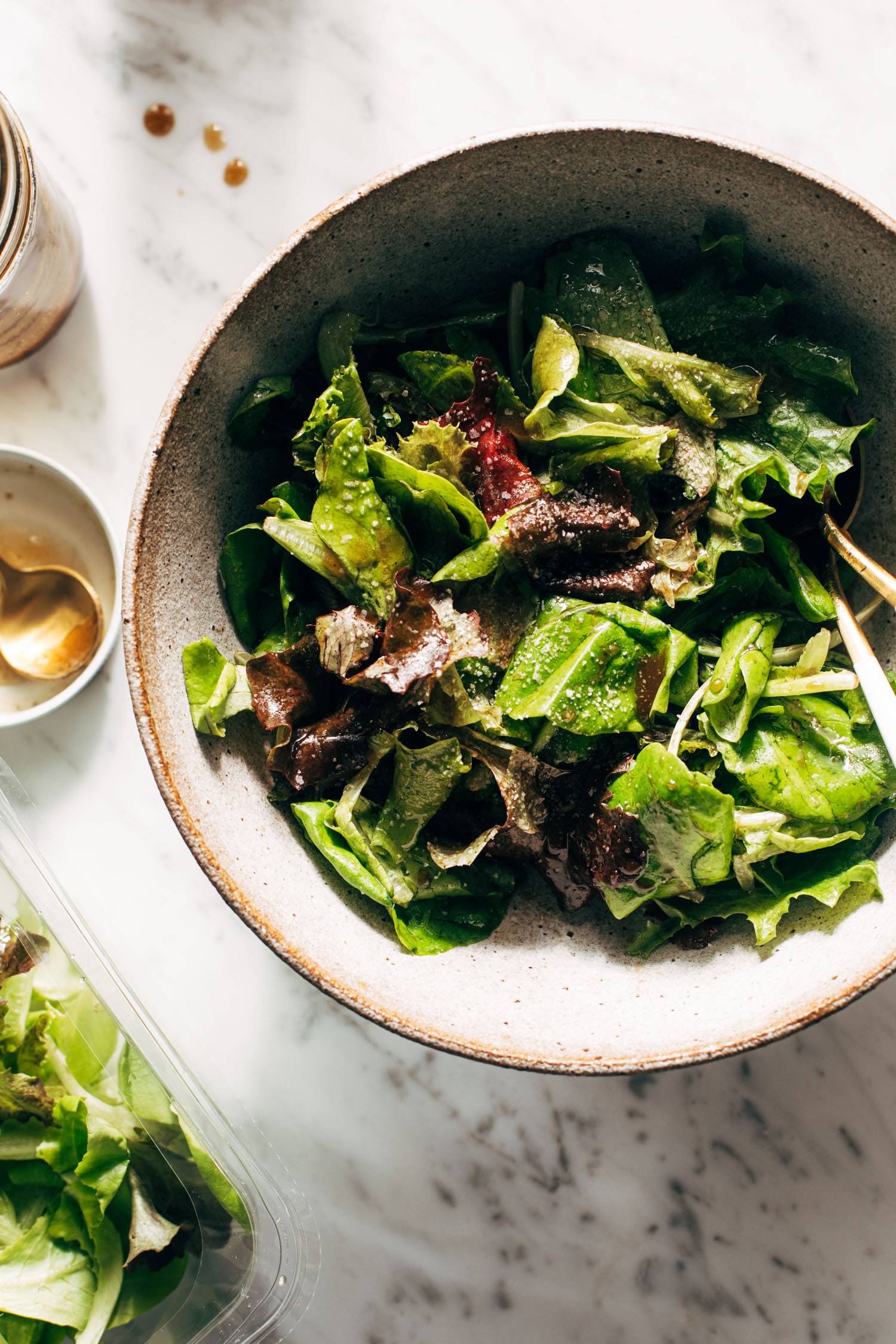 Green salad in a bowl with dressing on the side.