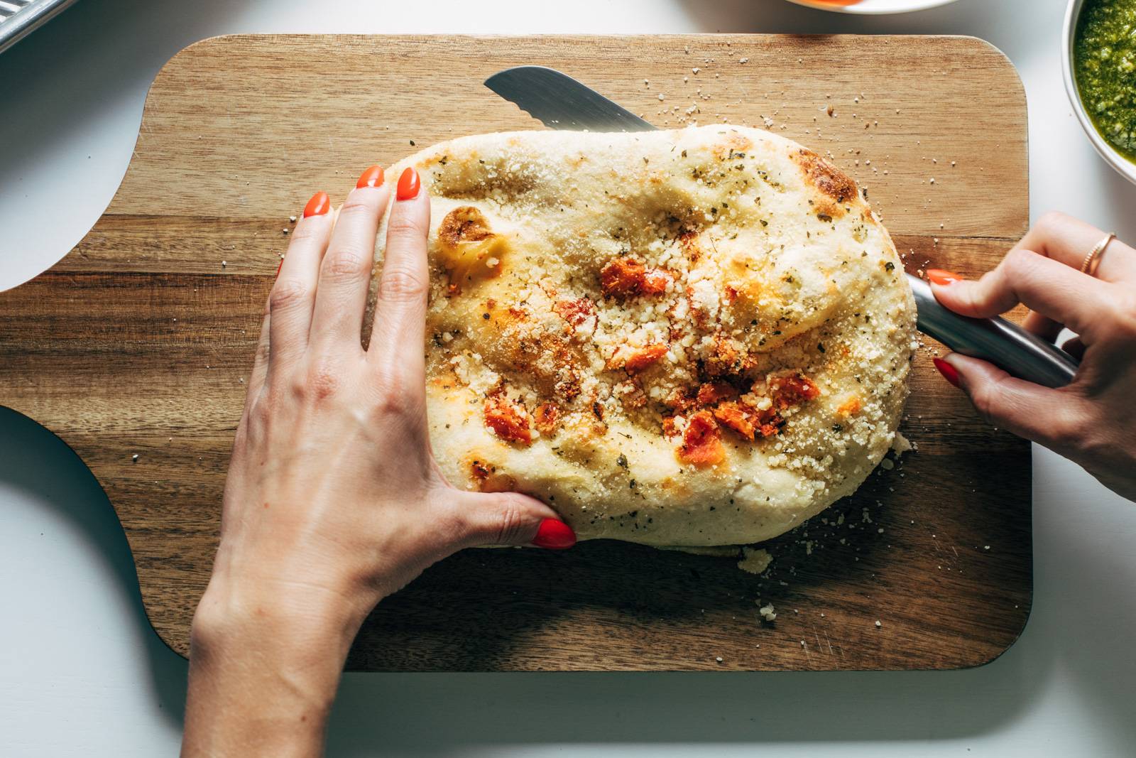 White hand cutting a piece of focaccia bread