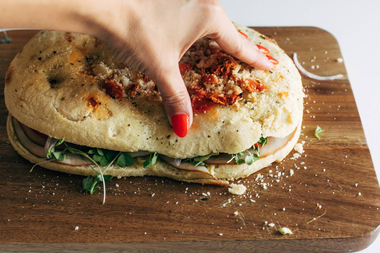 Top layer of focaccia bread being added to a turkey sandwich