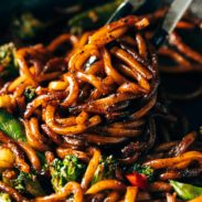 Udon Noodles mixed with fried vegetables and some black pepper in a cooking pan.