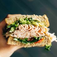 Person holding a turkey sandwich cut in half.