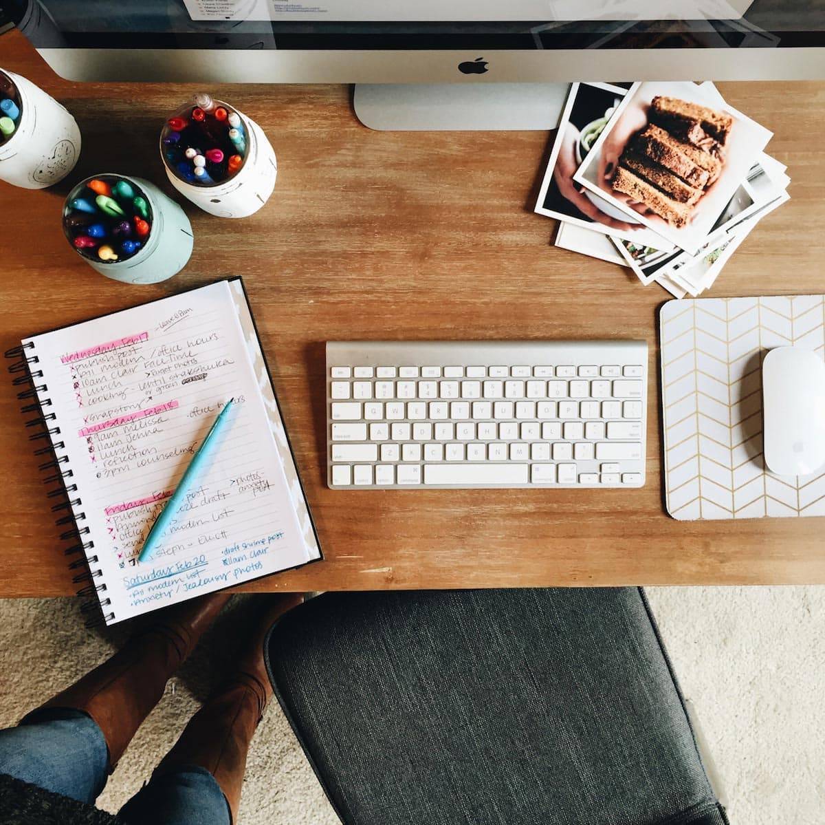 A computer desk with a notepad and photos on it.